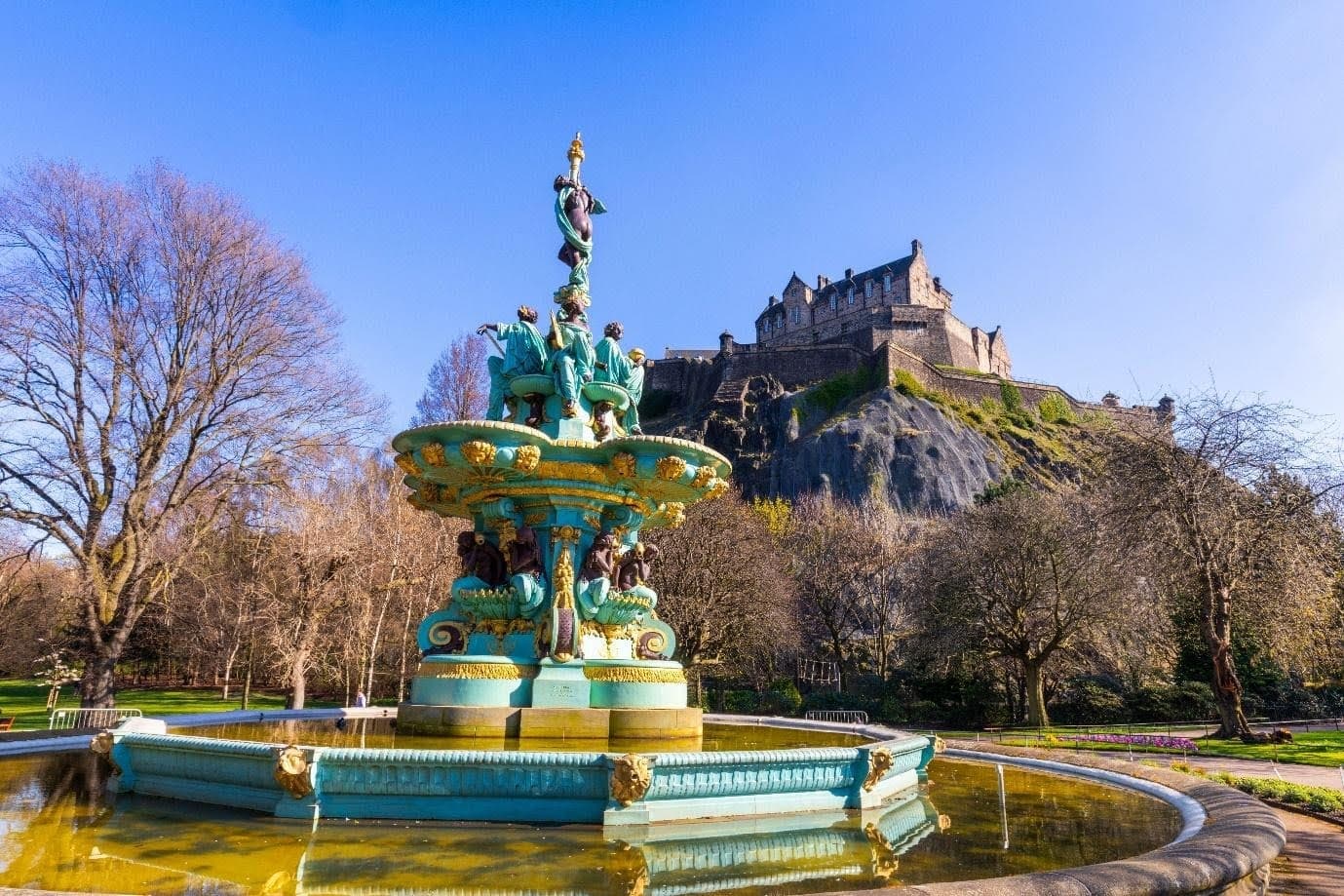 fountain in front of edinburgh castle on a blue sky day
