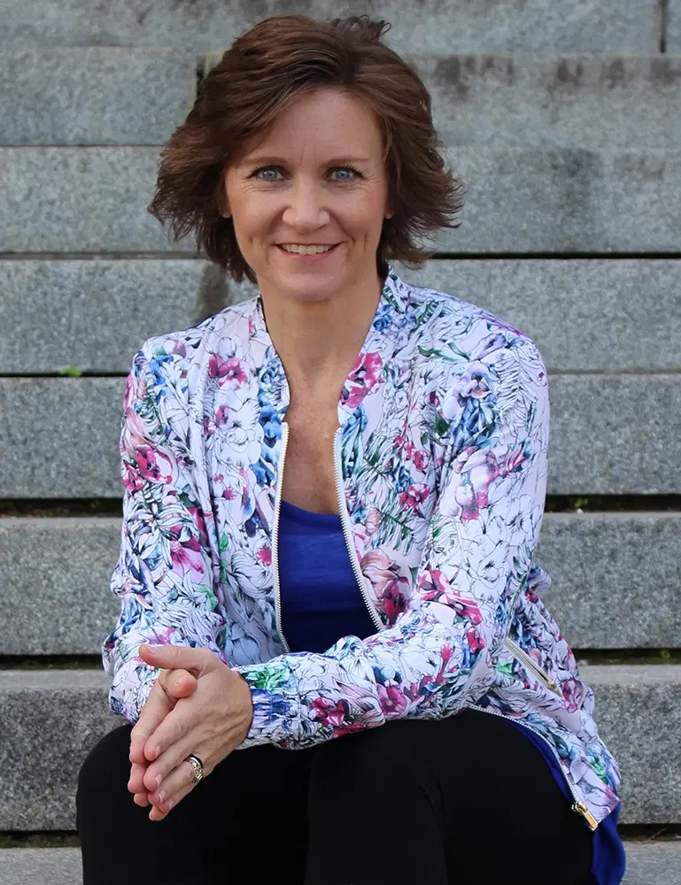 Lori Ann King, smiling, sitting on cement steps