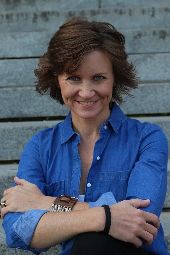 Lori Ann King, smiling, sitting on cement steps