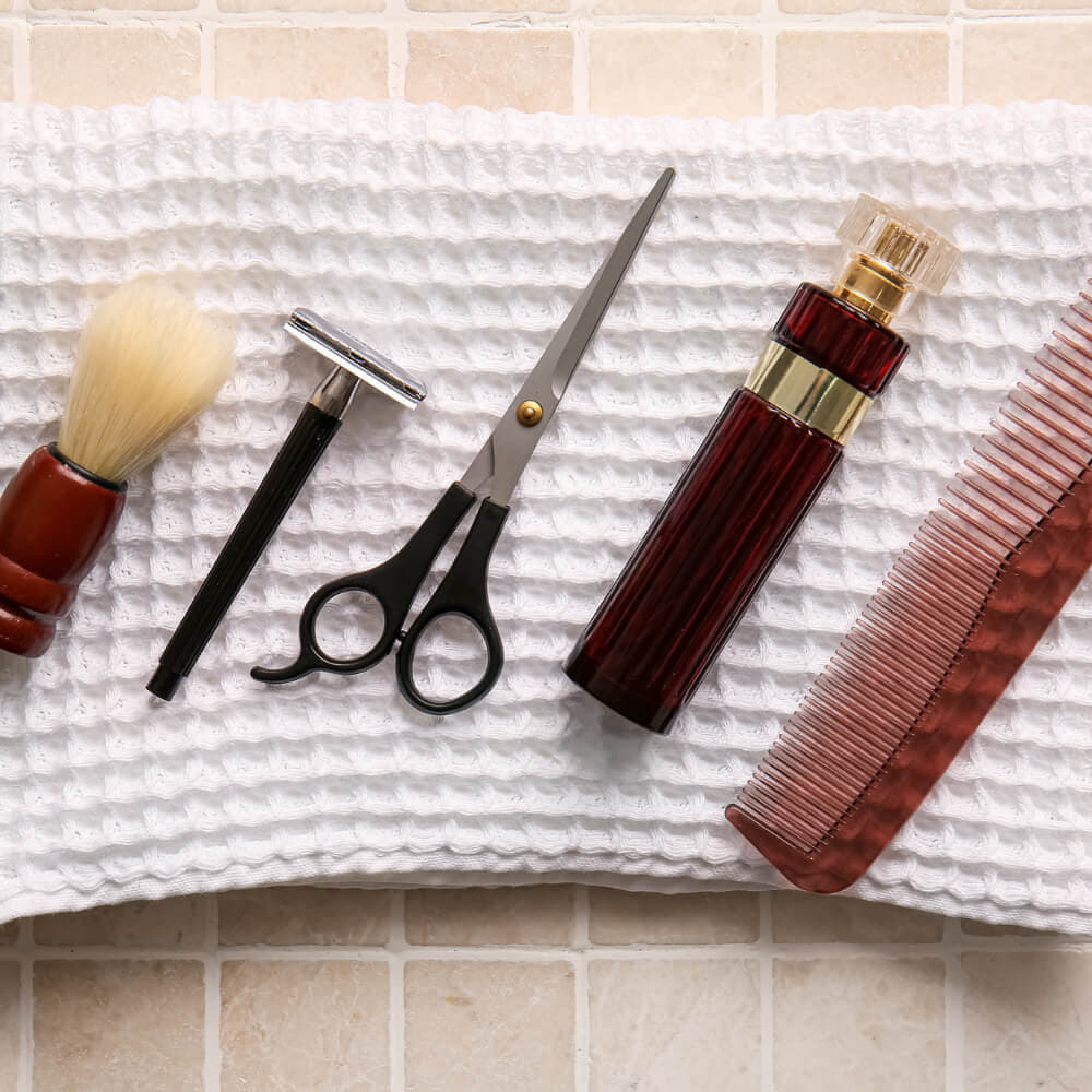 Classic men's grooming kit with shaving brush, comb, scissors, and cologne on a towel.  Meaningful gift for Dad from Son.