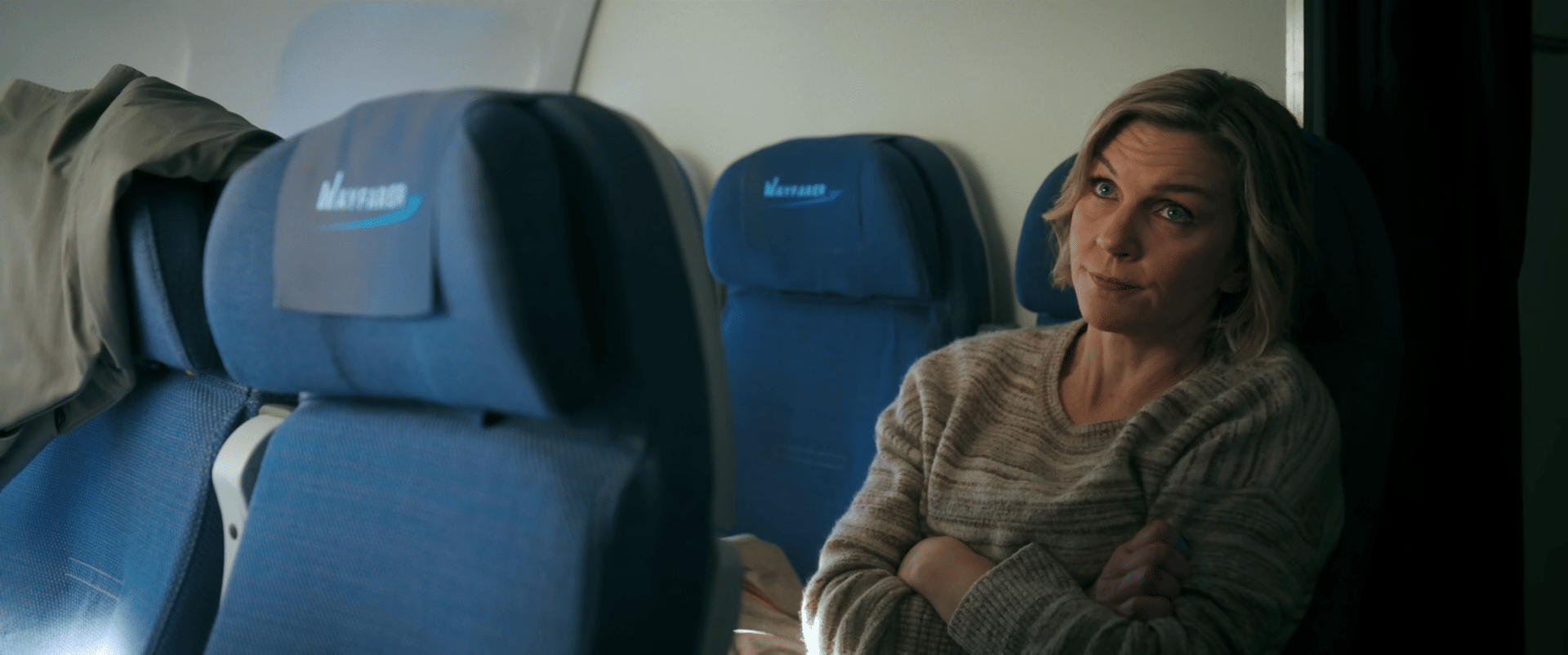 Rhea Seehorn as Carol Sturka on airplane in Vince Gilligan's Pluribus Apple TV series