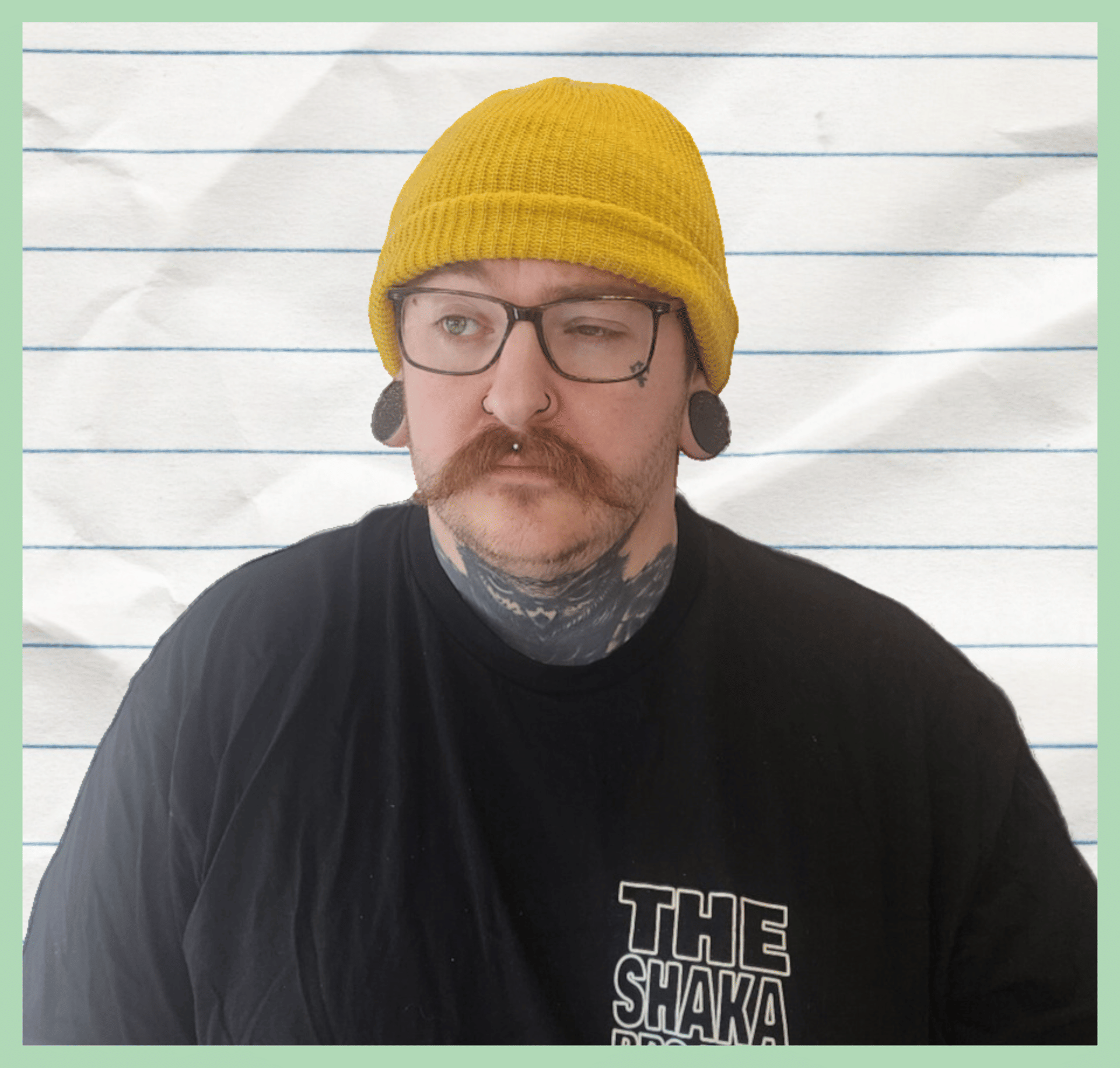 Carter in a mustard yellow beanie wearing glasses with a stylish moustache looking frustrated