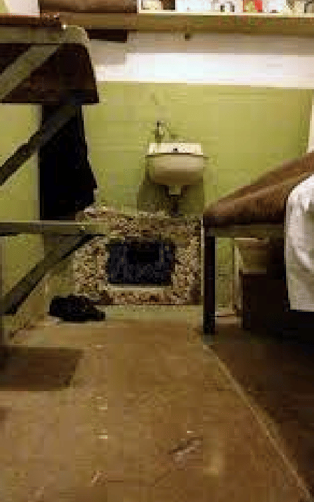 A hidden hole behind a grate in an Alcatraz cell, revealing the tunnel the inmates dug during their escape plan.