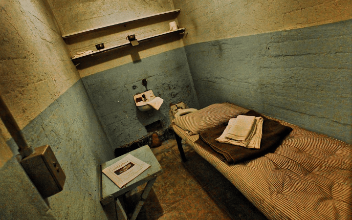 A small prison cell in Alcatraz with a bed, toilet, and sink, illustrating the harsh conditions inmates endured.