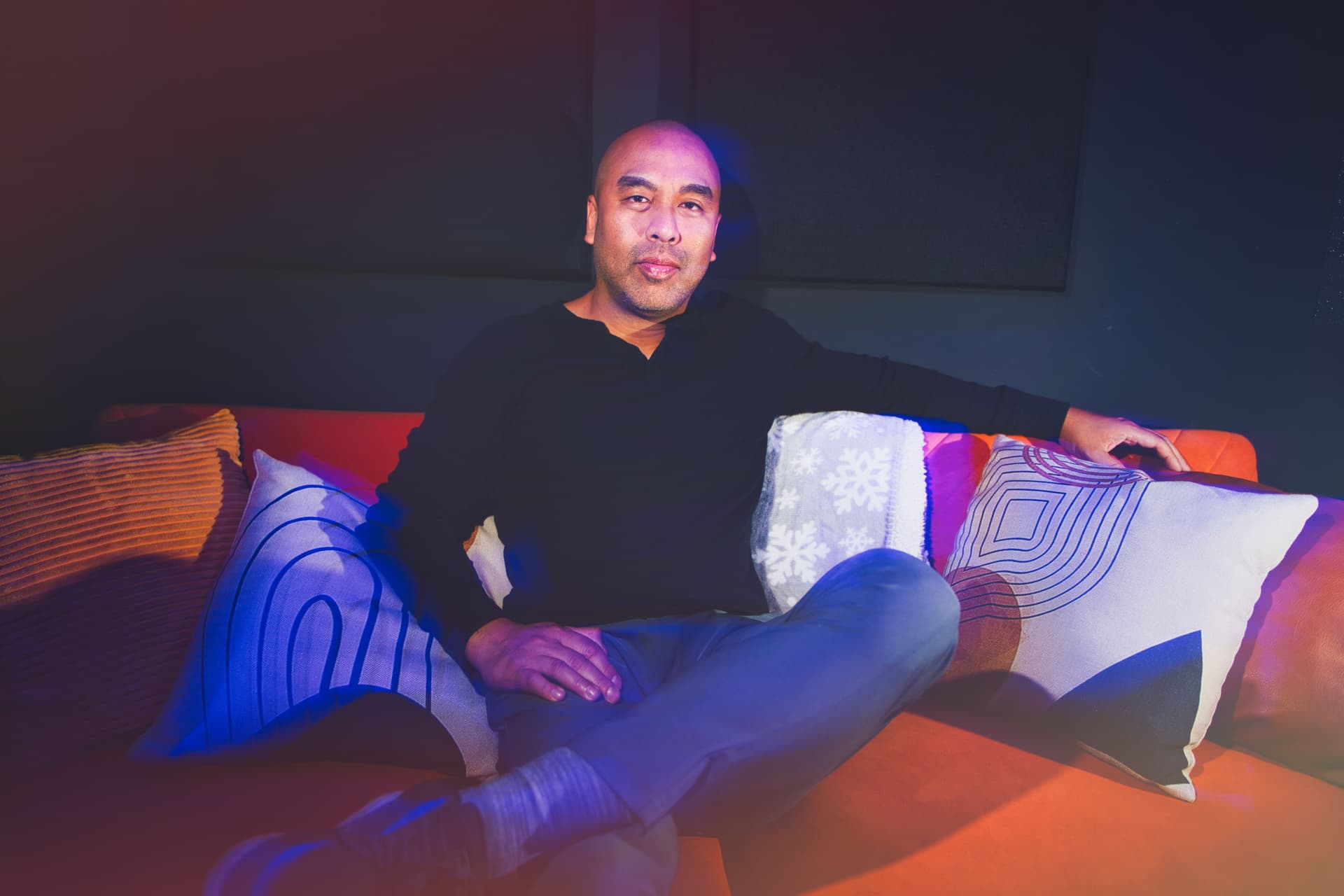 Jet Bunditwong, podcast host, sitting on a couch in the podcast studio